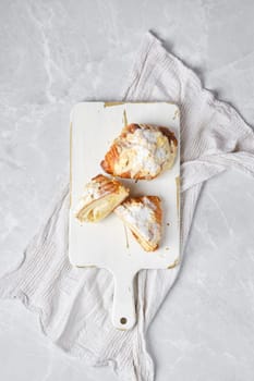 Top view of fresh croissant with caramel and peanut shavings on wooden serving board