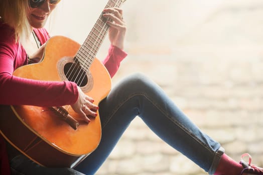 Closeup of young happy hipster woman plays the guitar with copyspace background. Summer fun and youth lifestyle concept.