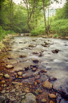 Beautiful forest river motion landscape. Water stream cascades in wood. Fine art wallpaper background.