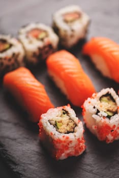 Traditional japanese cuisine. Sushi set with salmon and tuna fish on black sushi board.