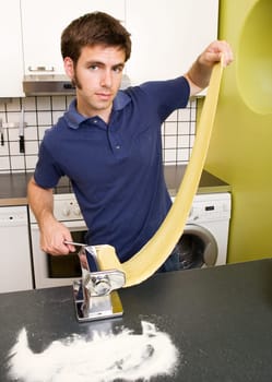 a young man making pasta at home in the kitchen