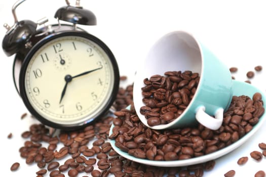 Cup with coffee grains and a black alarm clock