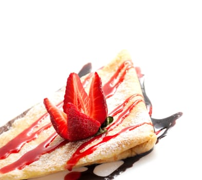 Closeup of tasty crapes with chocolate topping, sugar and strawberry on white background. Sweet dessert pancake homemade recipe with copyspace.