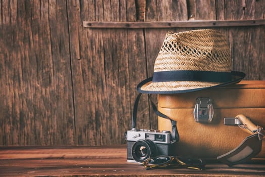 Vintage case, hipster hat, and retro camera on wooden background still life. Summer holiday vacation and adventure traveling concept with copyspace.