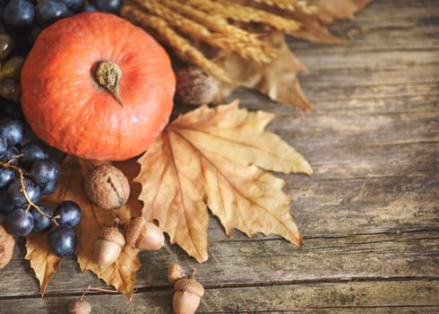 Happy thanksgiving holiday concept. Top view of autumn leaves, pumpkin, and fruits on rustic wooden table with copyspace.