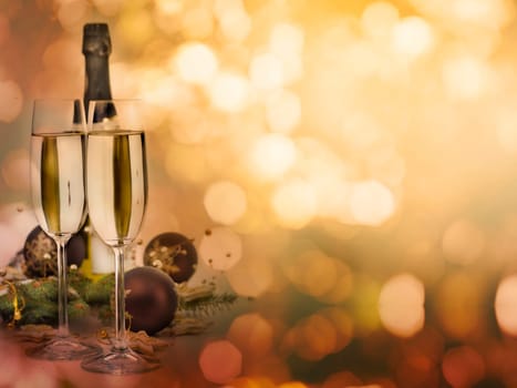 Two champagne glasses and christmas decoration with shiny bokeh lights background with copyspace. Christmas and New Year celebration party design.