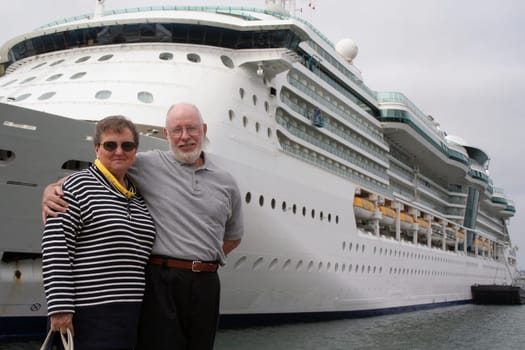 Senior couple ready for another cruise in front of a cruise ship.