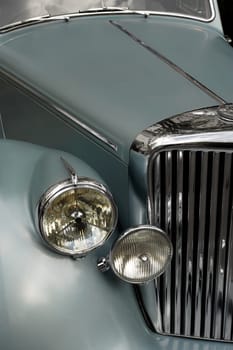 The chrome grill and headlights of an antique classic car.  Slightly desaturated.