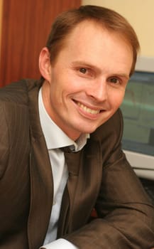 The happy young businessman sits at office