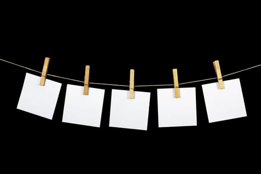 clothespins with paper on black background