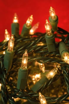 Shallow depth of field image of tangled illuminated Christmas lights.  Focus is on the middle bulb.