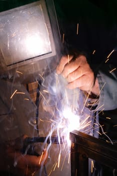 A welder using a mig torch to attach two pieces of metal.