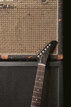 An electric guitar leaning up against an old vintage amplifier.