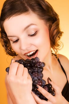 a glamorous girl holding some grapes in her hand