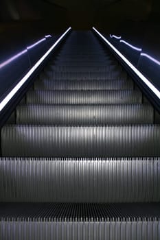 An escalator going up with colored stripes on both sides