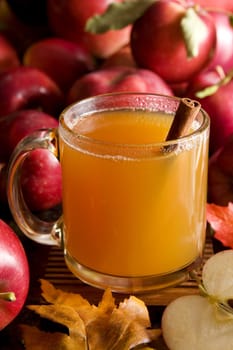A cup of hot apple cider surrounded by red apples