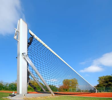 tennis court under blue sky, with focus on the net (wide angle)