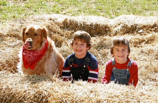 Little Farmers Sitting in the Hay with Their Dog