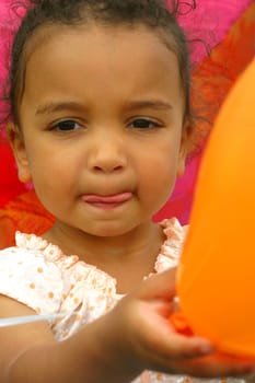 A beautiful mixed race little girl holding a balloon