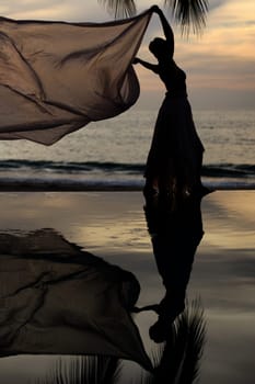 Woman with a scarf and her reflection in a pool by the ocean