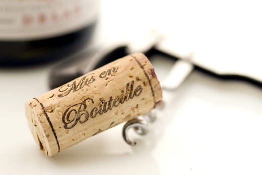 cork and corkscrew with a bottle of red wine