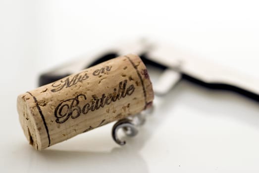 cork and corkscrew with a bottle of red wine