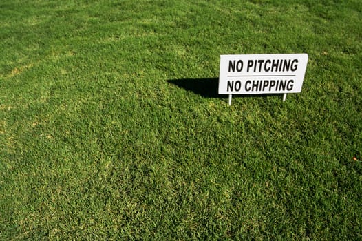 No Pitching, No Chipping sign in Lush Green Golf Course Grass.