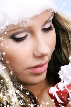 winter portrait of a smiling woman with a gift in her hands and snowflakes
