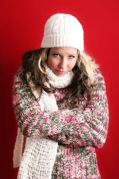winter portrait of a beautiful young woman is freezing with a cap and a scarf