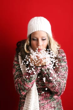 winter portrait of a beautiful young woman with a cap and a scarf and flying snow