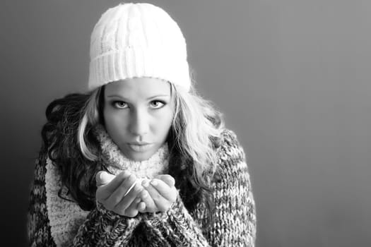winter portrait of a beautiful young woman with a cap and a scarf and flying snow