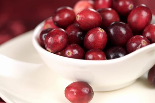 Bowl filled with cranberries on red background