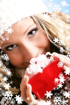 winter portrait of a smiling woman with a gift in her hands and snowflakes