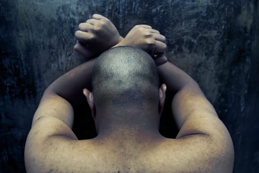 photo of a prisoner standing against a dirty wall inside a jail