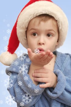 The boy blows on white snowflakes on a hand