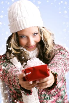 winter portrait of a smiling woman with a gift in her hands and snowflakes