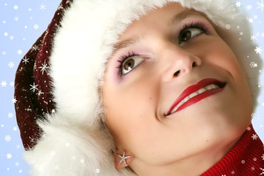 winter portrait of a young smiling woman with a christmas cap and snowflakes