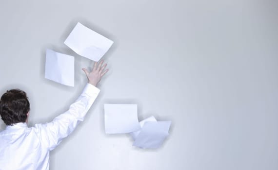 rear view of single man in white shirt raising his arm releasing stack of paper