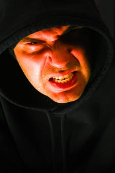 Angry hooded male looking at you with a slight bit of contempt.