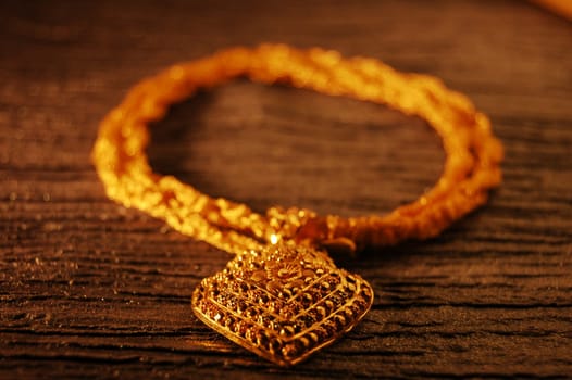 a necklace made of a golden pendant and a laced golden chain