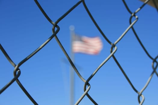American flag behind a chain link fence.