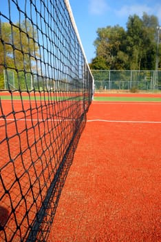tennis court under blue sky, the net as leading line (wide angle)