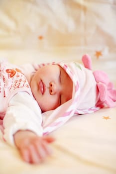 Lying sleeping baby with small teddy bear on bright background