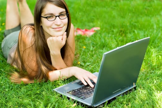 portrait of young woman surfing the internet outdoors on her notebook