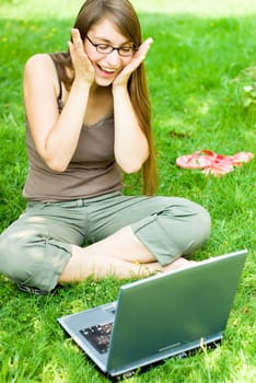 young excited woman surfing the internet outdoors on her notebook