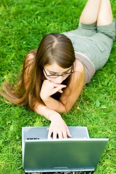 portrait of young woman surfing the internet outdoors on her notebook