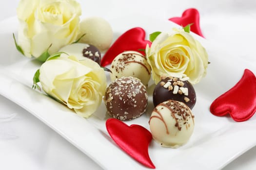 Delicious chocolate pralines with rose on white plate