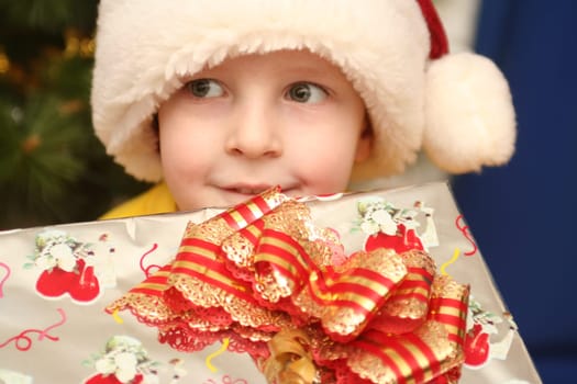 The boy in a New Year's cap and a gift