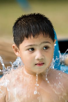 photo of cute asian kid playing with water fountain in swimming pool