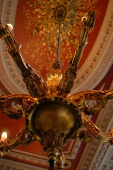 guilt chandelier hanging from ornate ceiling in 18th Century mansion in London